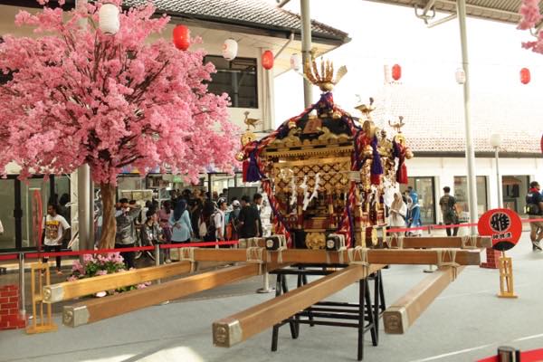桜の装飾と来場者に囲まれたお神輿